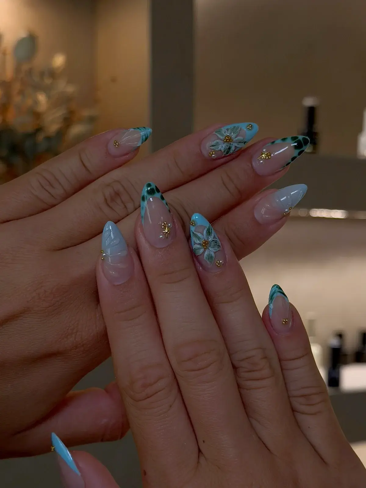 Mandelnägel mit blauer French, gemalten Blüten und Golddetails